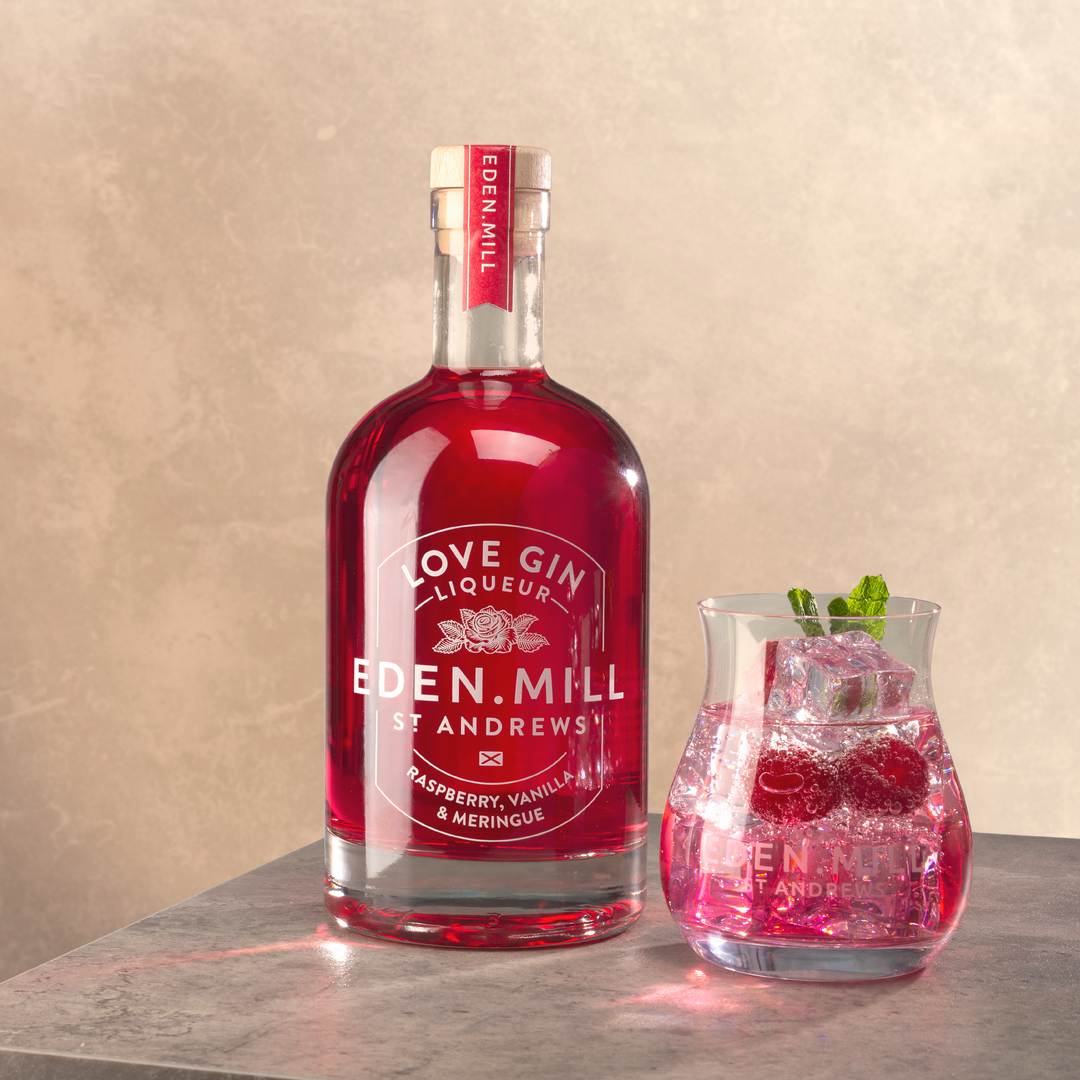 Bottle of Raspberry Vanilla Meringue Liqueur with Gin tulip glass of red cocktail
