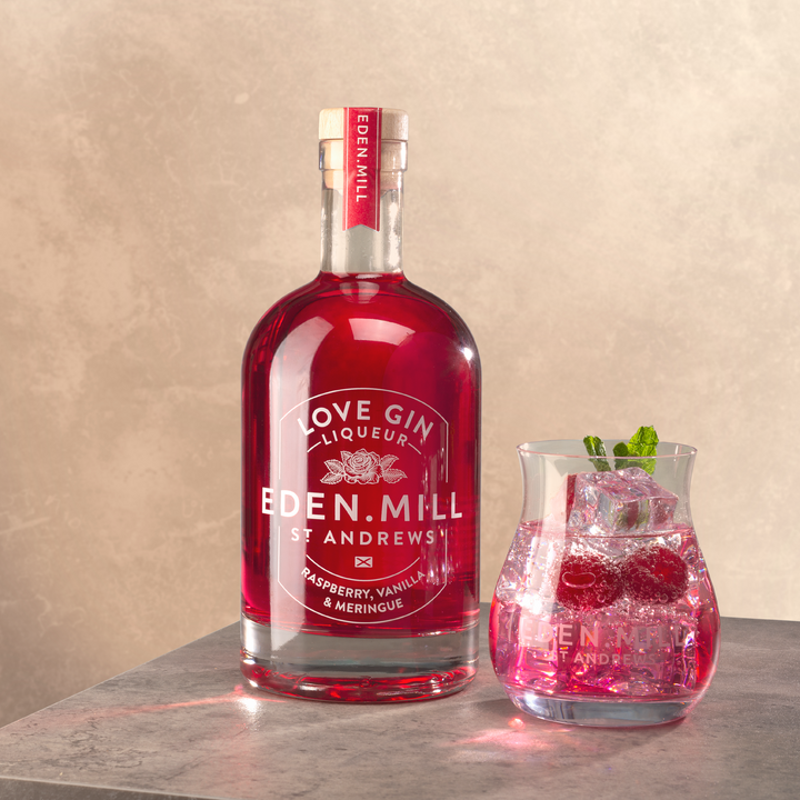Bottle of Raspberry Vanilla Meringue Liqueur with Gin tulip glass of red cocktail