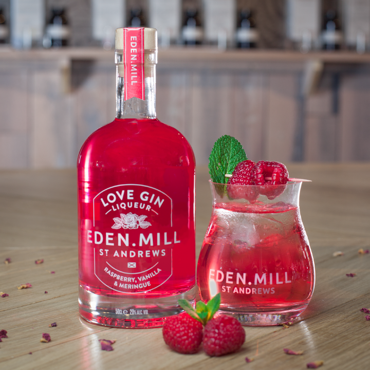 Bottle of Raspberry Vanilla Meringue Liqueur with Gin tulip glass of red cocktail