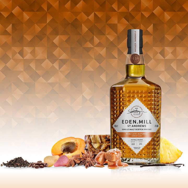 Rum Cask Single Malt Whisky Bottle on gold abstract background with fruit, toffee and fruit cake around base of bottle
